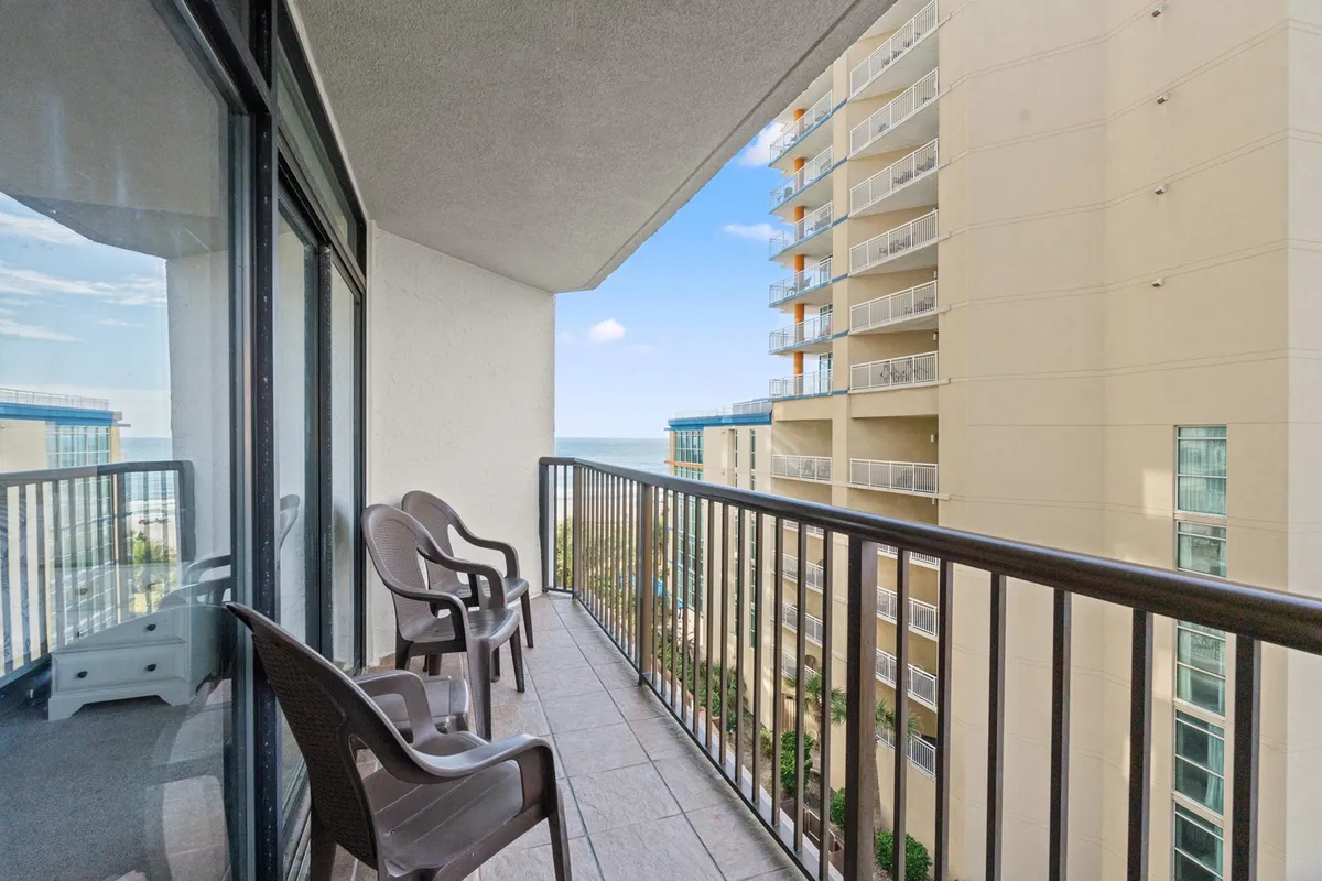 A tranquil private balcony features comfortable chairs positioned to face the expansive ocean view. The setting is serene, perfect for enjoying morning coffee or unwinding while listening to the waves.
