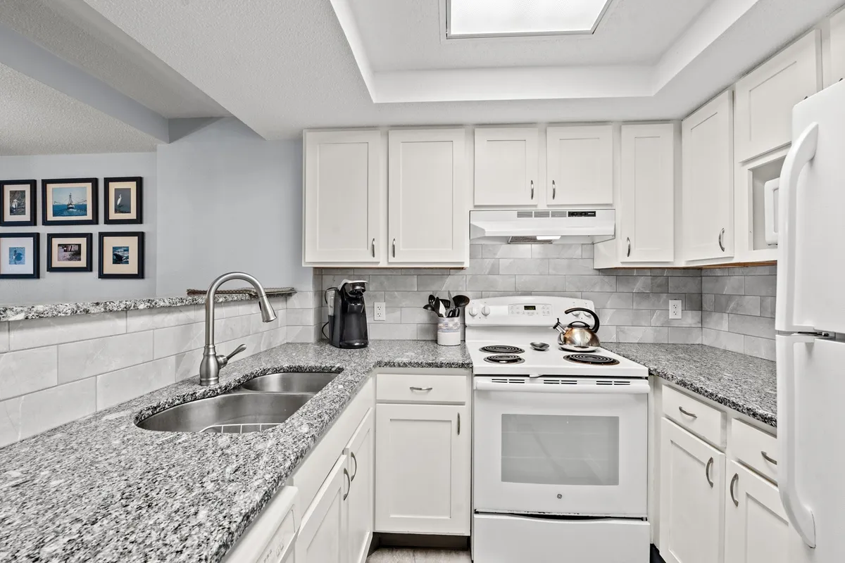 A bright and inviting kitchen interior featuring gleaming granite countertops, sleek modern appliances, and tasteful wall art. The open design allows for easy movement and interaction, with ample counter space visible for meal prep or serving. The scene hints at family gatherings and social cooking experiences, showcasing a kitchen that's both functional and stylish.