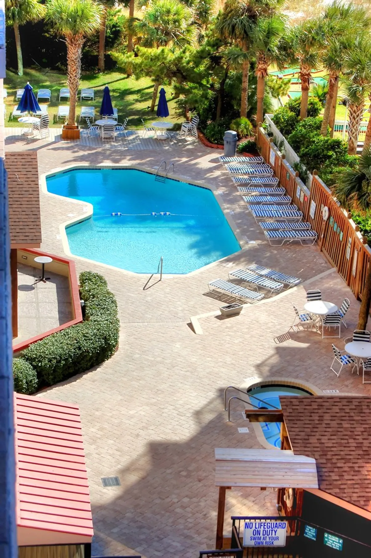 A lively swimming pool area with lounge chairs, palm trees, and a hot tub, inviting groups to relax, sunbathe, and socialize in a vibrant setting. The layout encourages group gatherings and poolside fun, reflecting the resort’s communal atmosphere.
