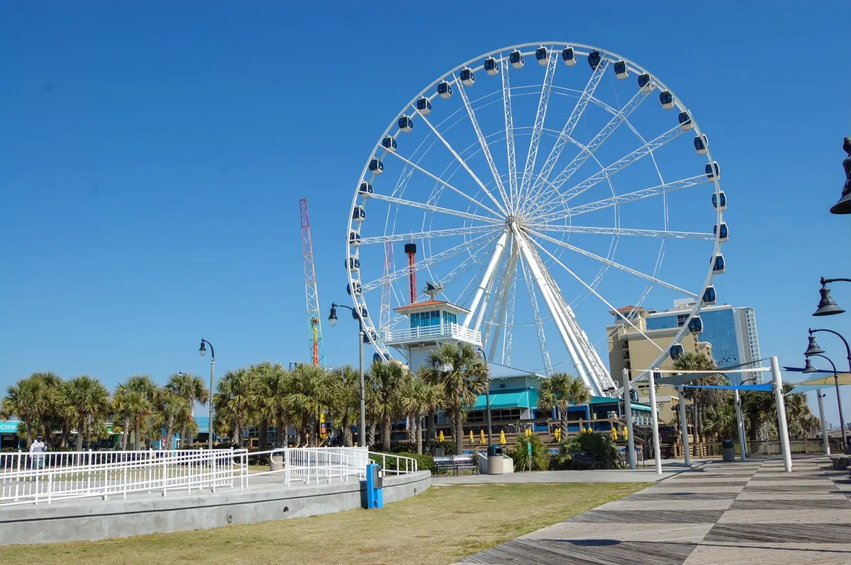 This image features the iconic Myrtle Beach Ferris wheel, palm trees, and the bustling boardwalk, capturing the energetic vibe of local attractions and group-friendly activities. It highlights the lively atmosphere of the area, perfect for group outings and adventure.